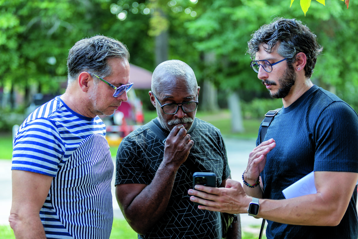 Three men looking at a cell phone in discussion.