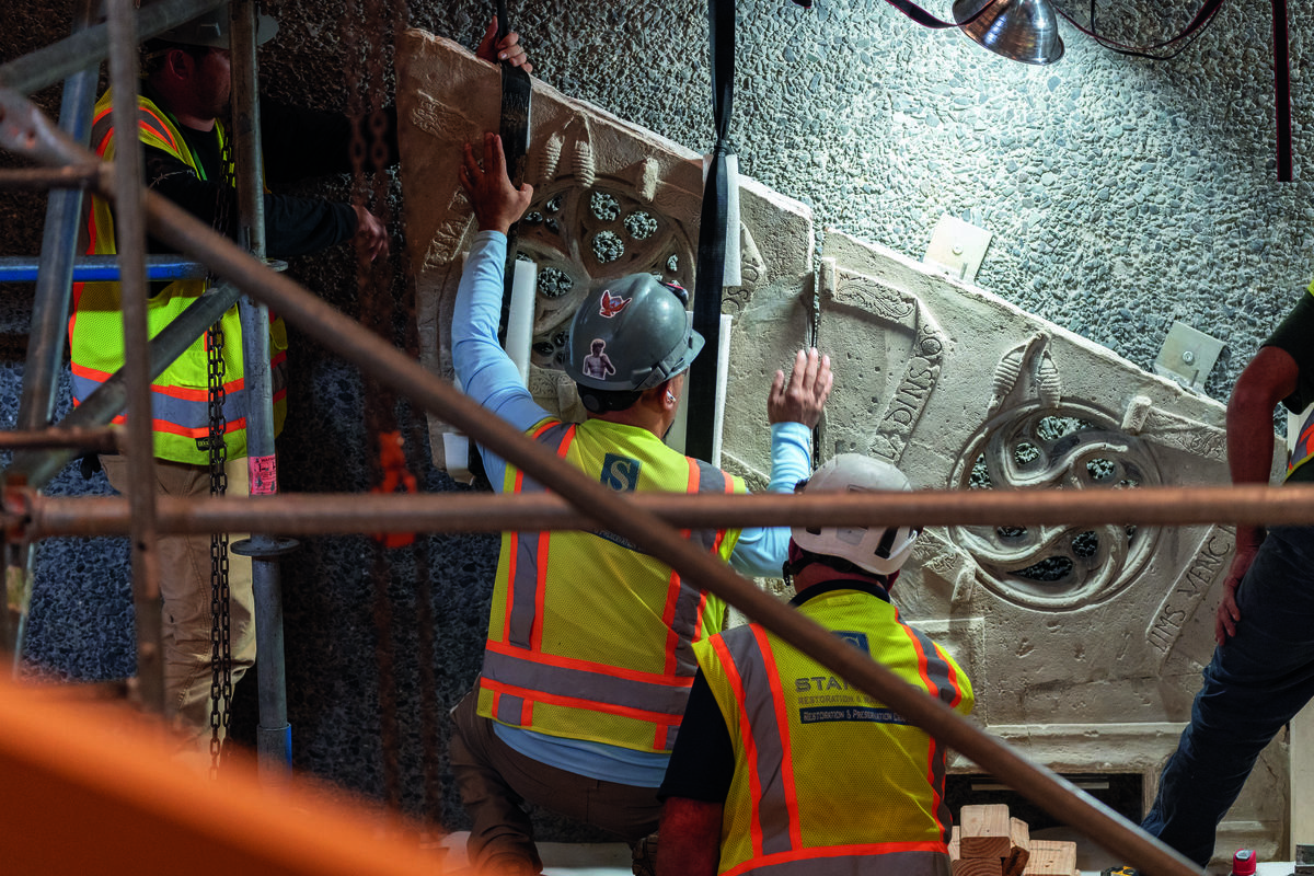 Installation team members fit together two large stone pieces of the stairway.