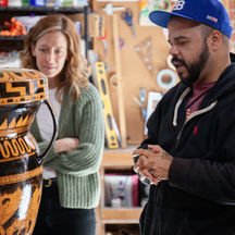 two people discussing a ceramic vase