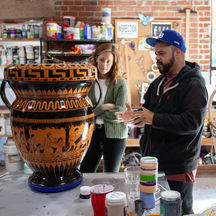 two people examining a large ceramic vessel