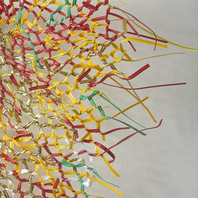 Red, yellow, and green twist ties that have been woven together into a mesh pattern
