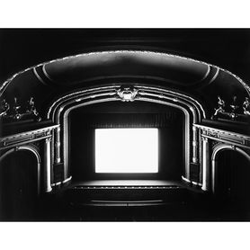 Black and white interior view of a theater with a screen glowing bright white.