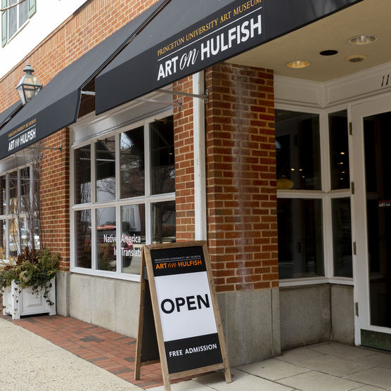 brick storefront with awnings and a sign out front on the sidewalk