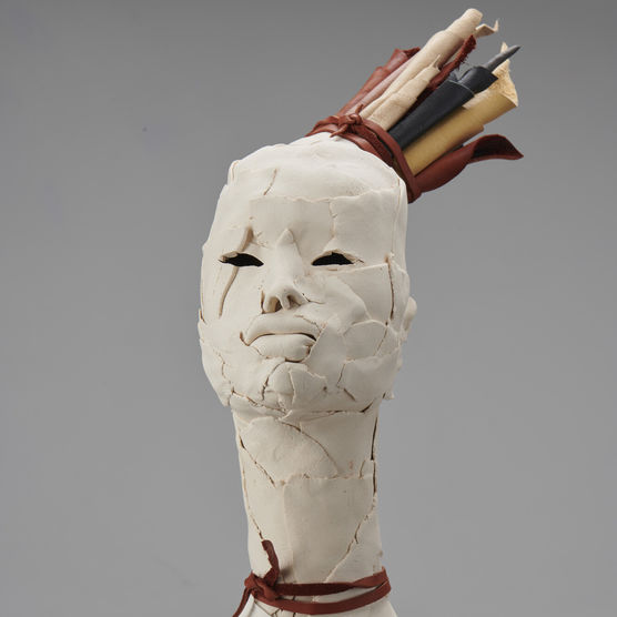 sculpted bust with visible fingerprints and pieces of clay on face, headpiece sticks out to right