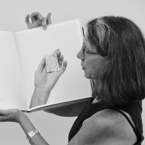 A woman holding a book open showing a photo of a hand.