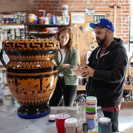 two people examining a large ceramic vessel