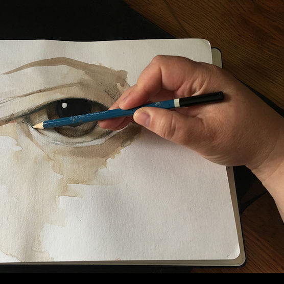 Hand of artist holding pencil brush over drawing