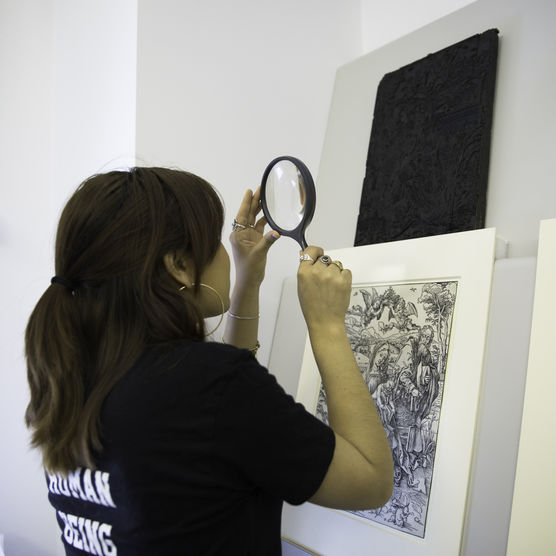 McCrindle intern examines work in the collection with a magnifying glass