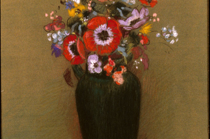 A tall, dark vase filled with variously colored flowers.