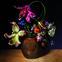 A round vase filled with lush flowers in bloom in many colors