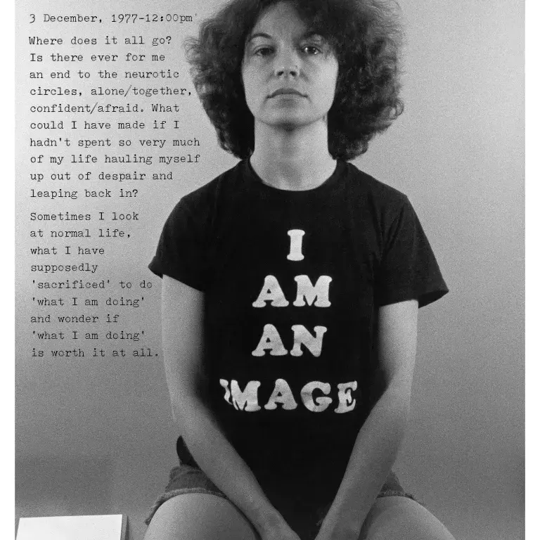 Black-and-white photograph of a woman sitting in a tshirt that says "I am an image."