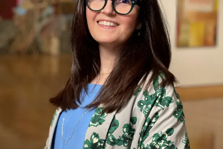 A smiling woman stands in a gallery space.